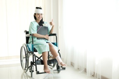 young woman in hospital wheel chair. happy smile as she got insurance money cover. beautiful chinese woman. medical, health insurance concept.