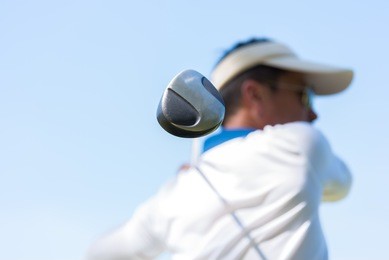 asian golfer hitting golf shot with club on course while on summer vacation. selected focus on player hand holding golf.