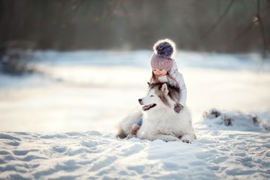 little girl with siberian husky are walking in the winter forest