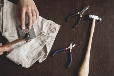 woman hands close up making wire wrapped jewelry top view preparation process dark. female girl bend  craft handmade copper  wire working tools on the table. handicraft people art concept.