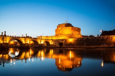 view of the castle of st. angelo or the mausoleum of hadrian and st. angel's bridge at night, italy