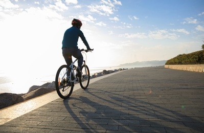 cyclist riding bike in the sunrise coast path