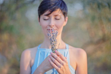 a girl holding a bouquet of lavender in her hands / a mature beautiful woman buried her eyes and dreams / copy space