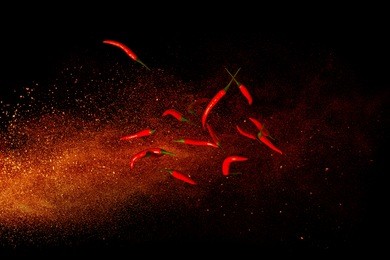 hot red pepper on a background of ground pepper. flying composition on black background