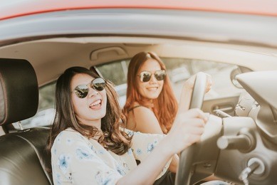 two happy asian girl best friends laughing and smiling in car during a road trip to vacation.