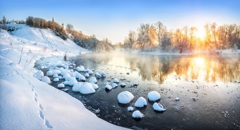the winter landscape on the river is an early sunny frosty morning and snow hummocks in the water near the shore, and a temple on the high bank of the river