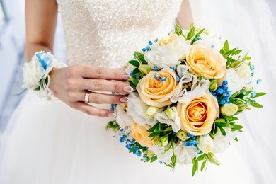 the girl in a white dress standing and holds a beautiful bouquet of white, orange flowers and greenery. wedding. bouquet.