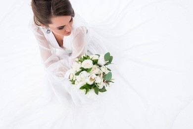 overhead view of young bride in dress holding wedding bouquet, isolated on white