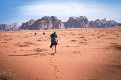 two hikers in a sand desert. tourist friends in jordan natural park wadi rum.group of backpackers walking on the road. natural background.