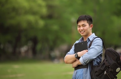 college student holding book on the park