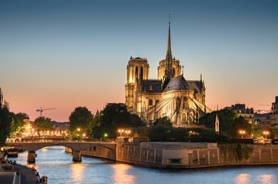notre dame de paris, france at sunset with view of seine river and bridge