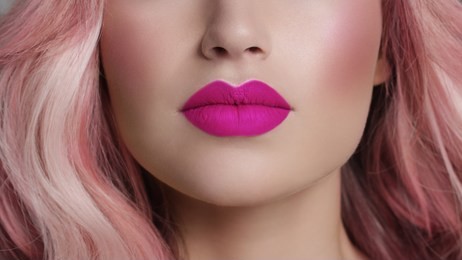 close-up of woman's lips with fashion bright pink make-up. beautiful female mouth, full lips with perfect makeup. part of female face. choice lipstick. pink wavy hair of a barbie doll