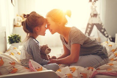 morning awakening. mother wakes her daughter in bed in morning
