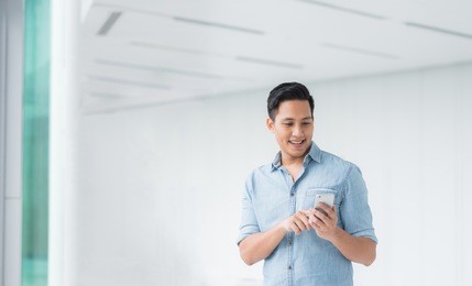 happy asian man using smartphone mobile in modern building 