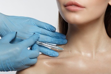 close up of surgeon hands in glove injecting rejuvenating liquid into female neck. beauty concept