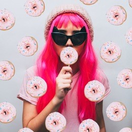 the girl in glasses and pink beanie hat eats a donut on a stick. fashion food minimalism. collage
