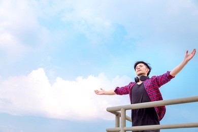 portrait freedom handsome guy: attractive handsome young man rise arms up and feels relaxed. cool guy is breathing deeply fresh air. glamour man loves travel and see beautiful view, sky. copy space