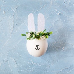 easter shabby chic background with egg bunny in flower wreath on blue .