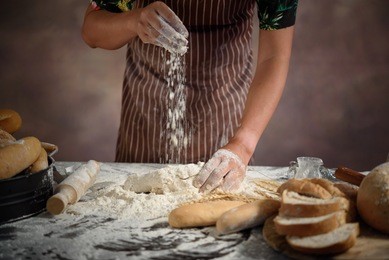 baker prepares bread. baker sprinkle and eggs the dough with flo