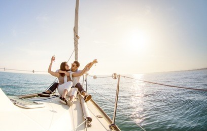 young couple in love on sail boat with champagne at sunset - happy people lifestyle on exclusive luxury concept  - soft backlight focus on warm afternoon sunshine filter - fisheye lens distortion