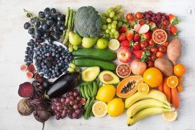 healthy eating concept, assortment of rainbow fruits and vegetables, berries, bananas, oranges, grapes, broccoli, beetroot background on white table arranged in rectangle, top view, selective focus