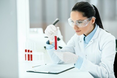 laboratory. woman doing medical research with blood. portrait of beautiful young female in white coat sitting at workplace and working with blood sample in lab. medical laboratory. high resolution