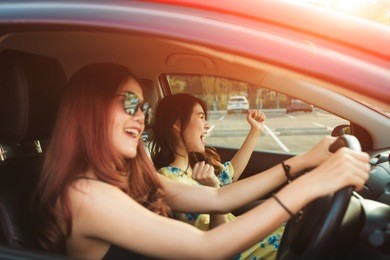 enjoying woman and friend  driving in red car summer vacation, holidays, travel, road trip and people concept .