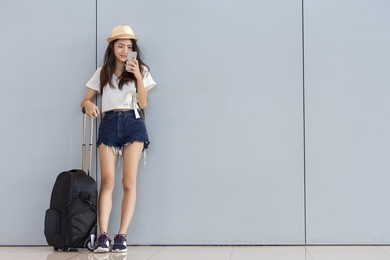 asian woman teenager using smartphone at airport terminal standing with luggage suitcase and backpack for travel in vacation summer relaxing waiting flight transport online check in or booking ticket