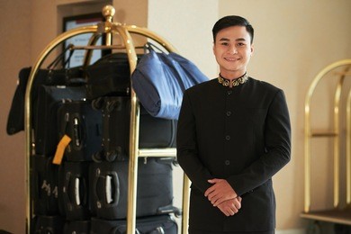 cheerful vietnamese porter and hotel baggage cart in the background