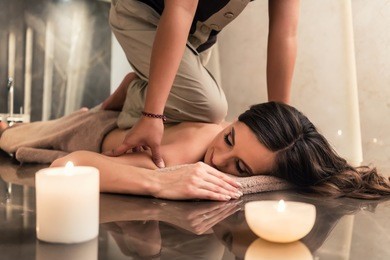 young woman lying down while enjoying the acupressure techniques of traditional thai massage at luxury spa and wellness center