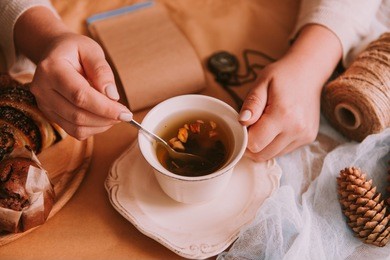 woman's hands holding cup of aromatic fruit tea? stirring slowly with spoon