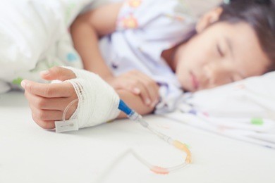 sick asian little child girl hand who have saline intravenous (iv) drip bandage is sleeping on bed in the hospital