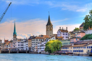 beautiful summer cityscape of the city zurich, switzerland, with the big crane at the river limmat and the fraumünster and st. peter churches