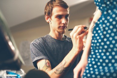 a young guy, a tattoo artist preparing for the session, draws a sketch on the body of the client in a welcoming environment