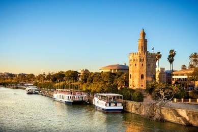 view of golden tower (torre del oro) of seville, andalusia, spain over river guadalquivir at sunset