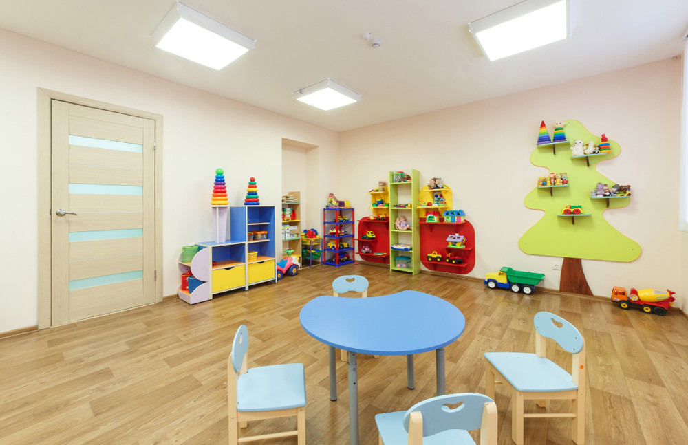 blue table for classes with children and light pink colored game room with in the kindergarten.