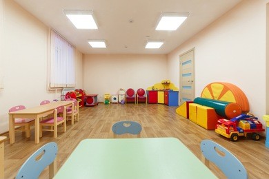 spacious light pink colored game room with in the kindergarten. table for classes on foreground