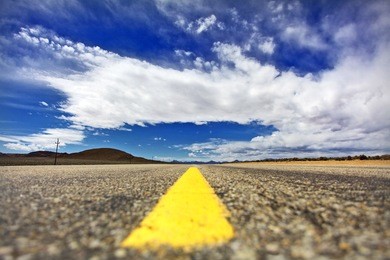 wide open road on a sunny summer day under a blue sky near the mountains and desert