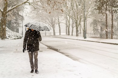 view of a man with an umbrella walking in the valentino public park in turin (piedmont, italy) during a heavy snowfall in winter.