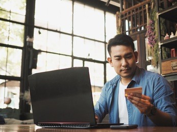 smart young asian man working with laptop during drinking coffee in working space.