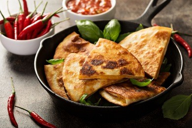 fried quesadillas with cheddar cheese and hot pepper in a cast iron pan