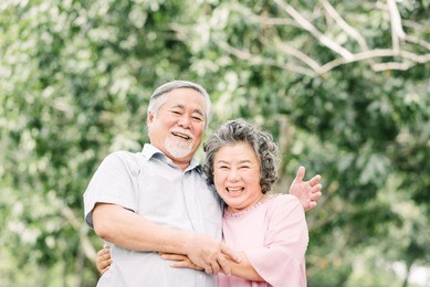 happy asian senior couple having a good time. they laughing and smiling while holding each other outdoor in the park.