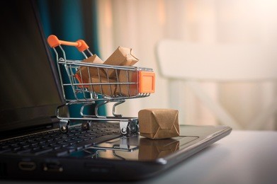 online shopping concept. shopping cart, small boxes, laptop on the desk