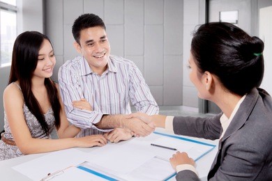 young couple shaking hand with real estate agent in a meeting