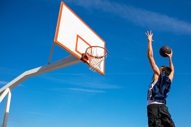 young basketball street player making slam dunk