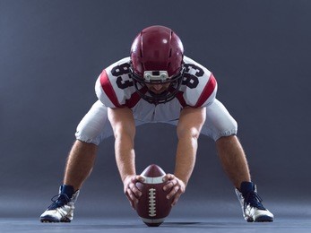 american football player getting ready before starting the game while standing against gray background