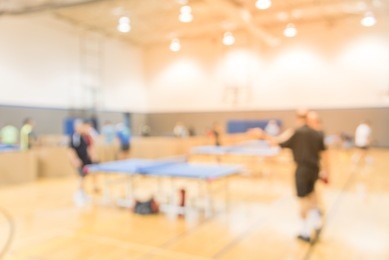 blurred motion people playing table tennis at recreation park in america. multiple indoor ping pong players compete at community sport activities.