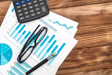  financial graphs with eyeglasses, pen and calculator on the workplace. top view.