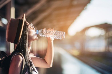 young woman back pack traveler drink fresh water in train station - outdoor asian traveler activity concept