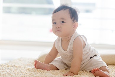 nine months old baby boy sitting on carpet. asian family at home, living lifestyle indoors.